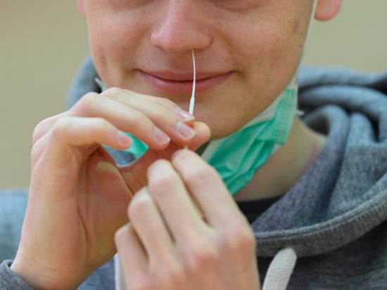 Ein Schüler des St.-Benno-Gymnasiums testet sich vor Beginn der Abiturprüfung in Katholischer Religion in der Turnhalle mit einem Schnelltest auf das Coronavirus. 