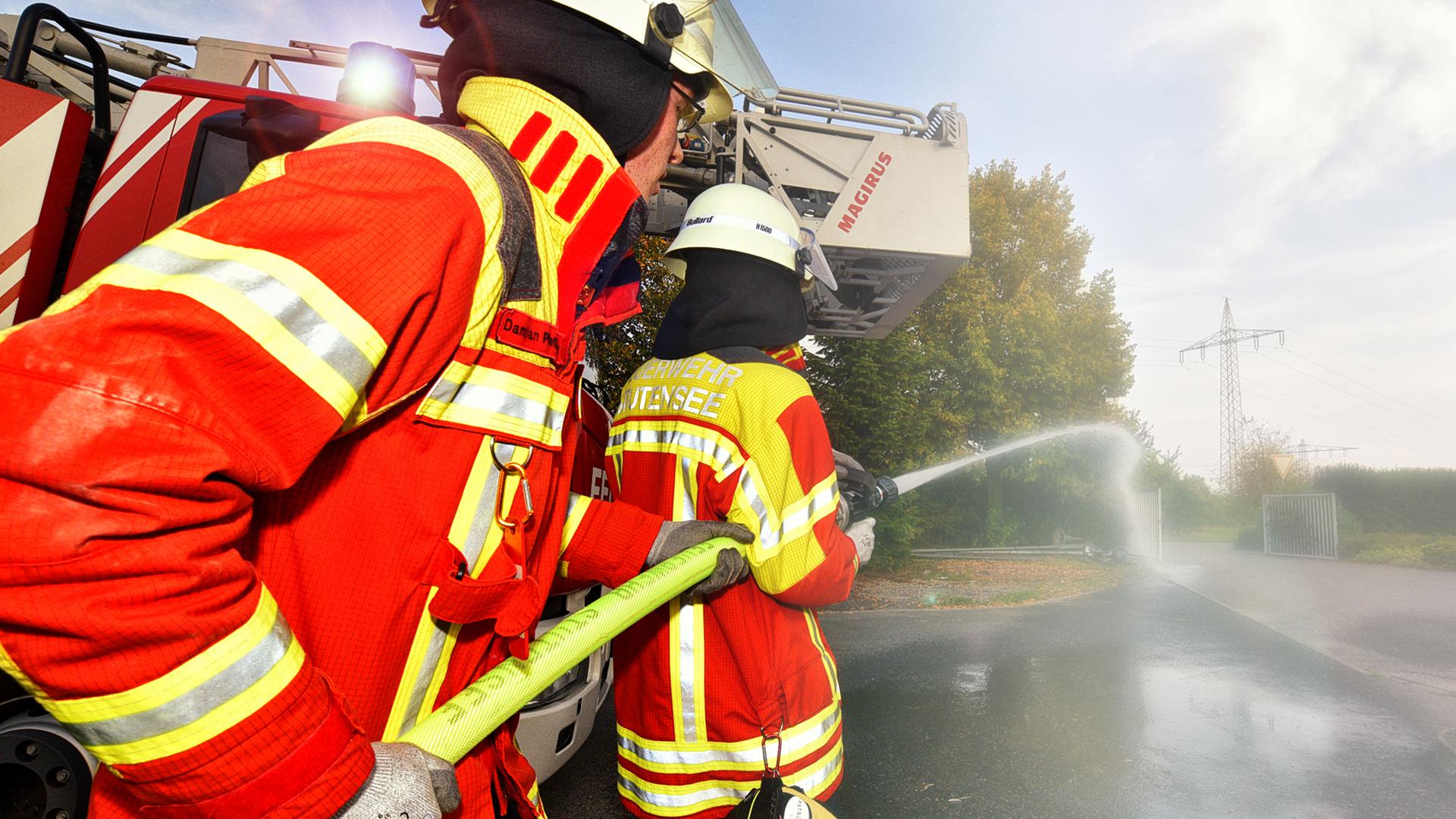 Mitglieder der Feuerwehr halten einen Wasserschlauch (Symbolbild).