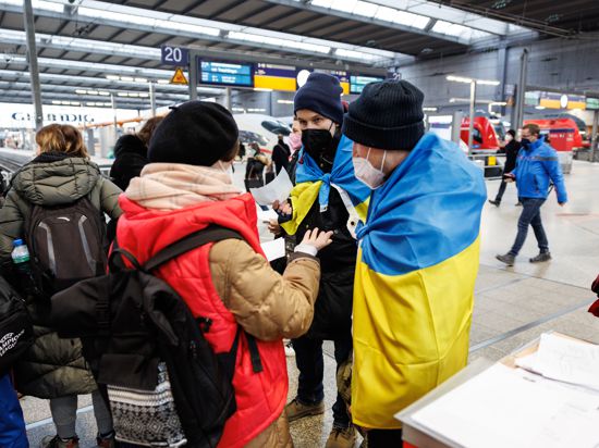 Zwei ukrainisch sprechende Helfer (rechts) sprechen an einem Info-Point am Münchner Hauptbahnhof für geflüchtete Ukrainer mit einer Frau aus der Ukraine. 