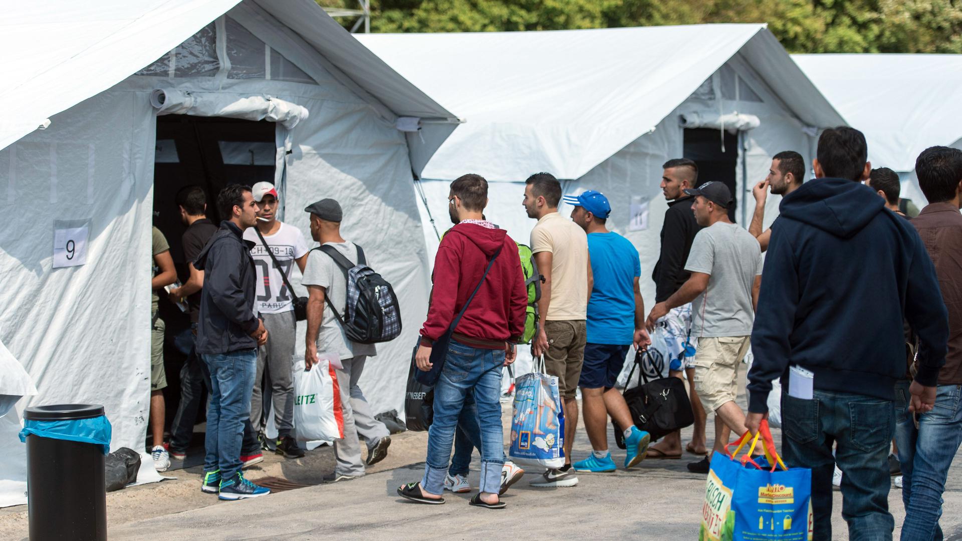 Flüchtlinge beziehen am 02.08.2015 in Neuenstadt am Kocher (Baden-Württemberg) ein temporäres Zeltlager. Die Flüchtlinge wurden in zwei Bussen von der überfüllten Erstaufnahmestelle in Ellwangen in das Lager, welches bis zu 200 Flüchtlingen Platz bietet, gebracht. Foto: Daniel Maurer/dpa ++ +++ dpa-Bildfunk +++