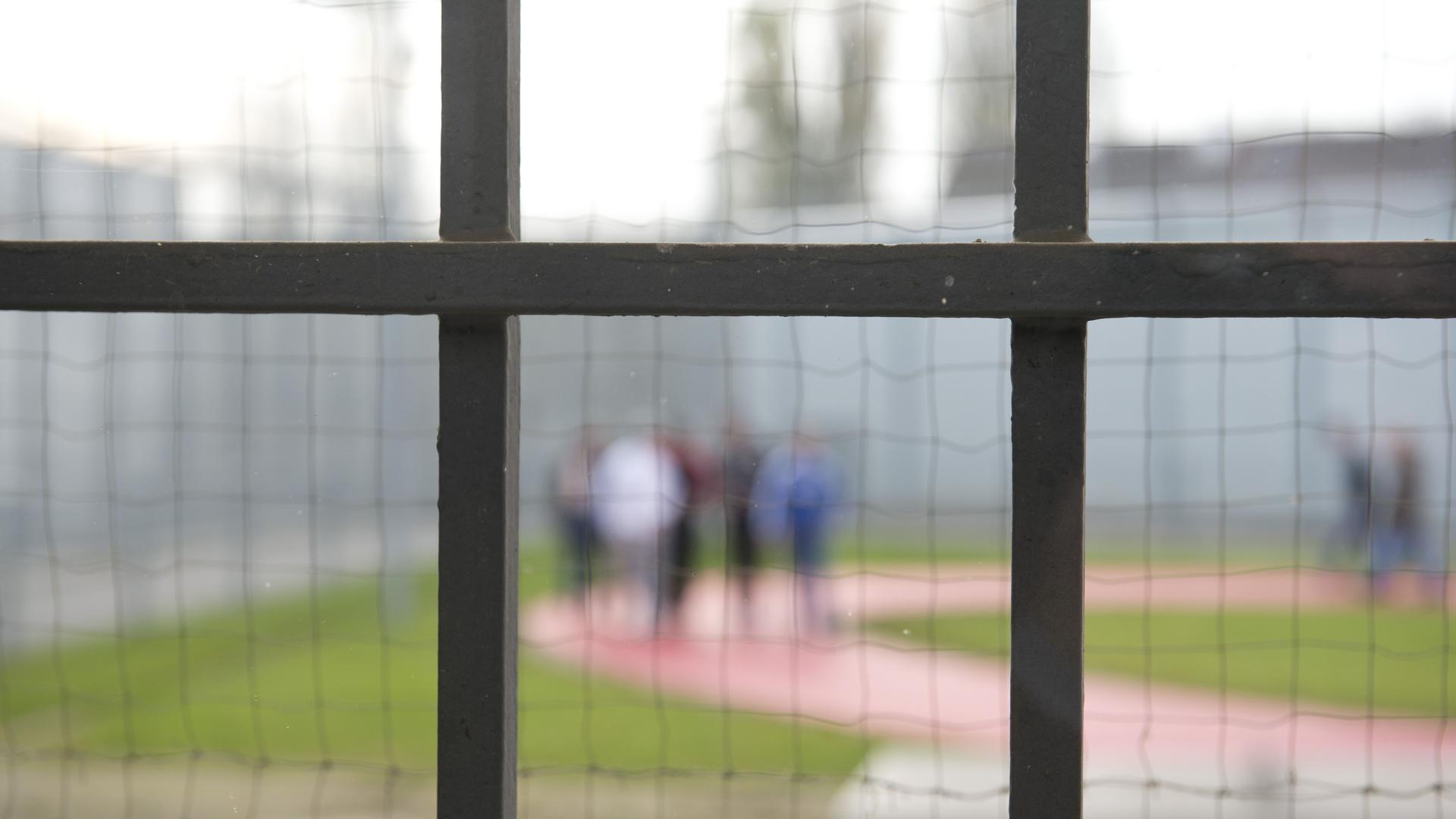 ARCHIV - Hinter einem Gitter laufen am 21.11.2014 Gefängnisinsassen der Justizvollzugsanstalt in Stuttgart (Baden-Württemberg) über einen Gefängnishof. Foto: Daniel Naupold/dpa (zu dpa "Gefängnisse als Brutstätte des Islamismus?" vom 01.03.2015) +++ dpa-Bildfunk +++