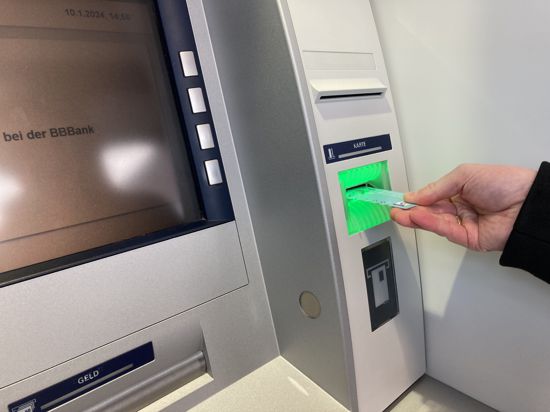 Ein Mann steckt eine EC-Karte in den Geldautomat der BBBank in Linkenheim-Hochstetten.