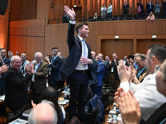 Manuel Hagel, Kandidat für den Landesvorsitz der CDU Baden-Württemberg, winkt beim Landesparteitag der CDU Baden-Württemberg nach seiner auf einem Stuhl stehend den Delegierten zu. Nach dem angekündigten Rückzug von T.Strobl will Manuel Hagel für den Landesvorsitz kandidieren. +++ dpa-Bildfunk +++