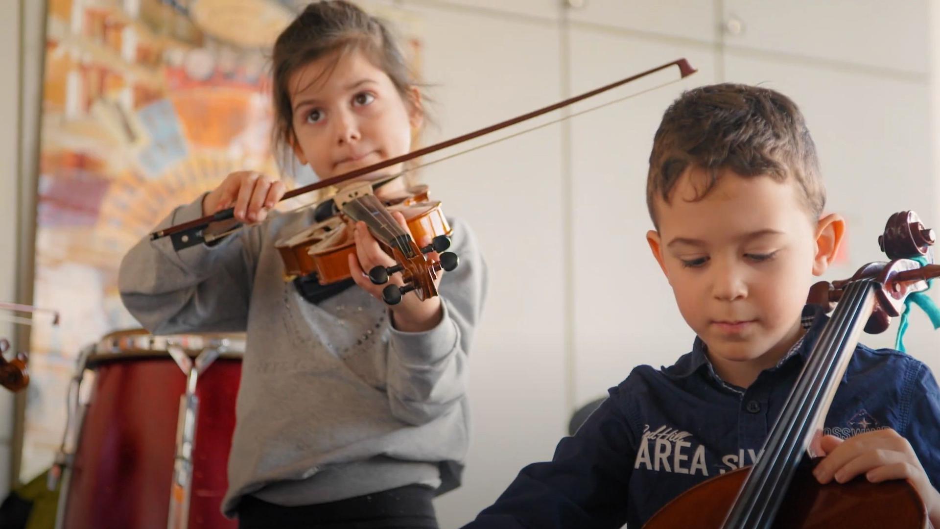 Zwei Kinder mit Streichinstrumenten.