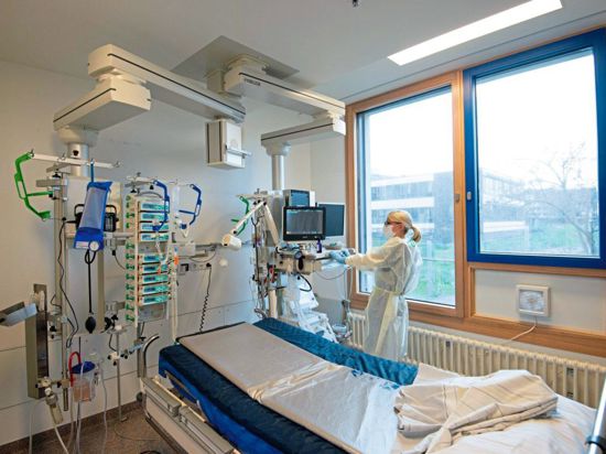 Eine Intensivpflegerin bedient vor einem leeren Intensivbett einen angeschlossenen Monitor