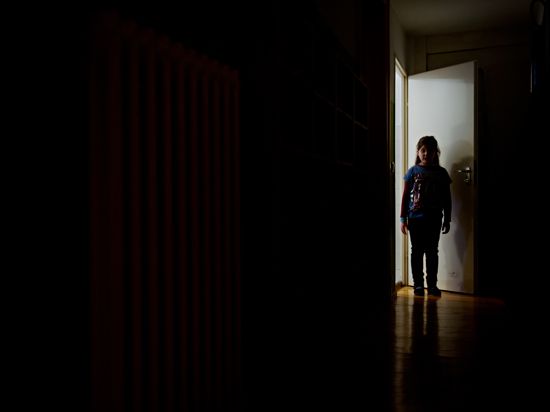 Ein junges Mädchen steht am Ende eines dunklen Flures.