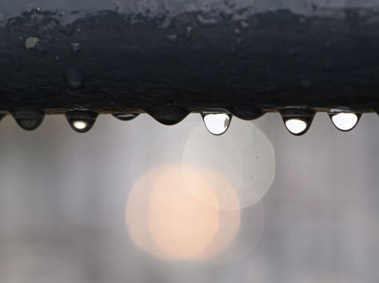 Regentropfen hängen an einem Geländer.