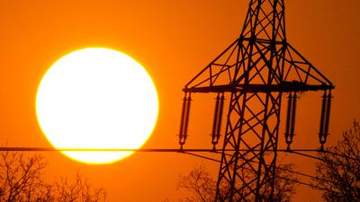 Die Sonne geht am 03.05.2013 nahe Rotenburg (Niedersachsen) hinter einer Hochspannungsleitung unter. Foto: Daniel Reinhardt/dpa +++(c) dpa - Bildfunk+++ | Verwendung weltweit
