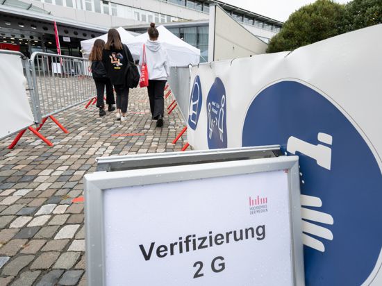 Baden-Württemberg, Stuttgart: Studenten laufen am Eingang der Hochschule der Medien an eine Kontrollstelle für einen Nachweis über eine Corona-Impfung oder -Genesung. 