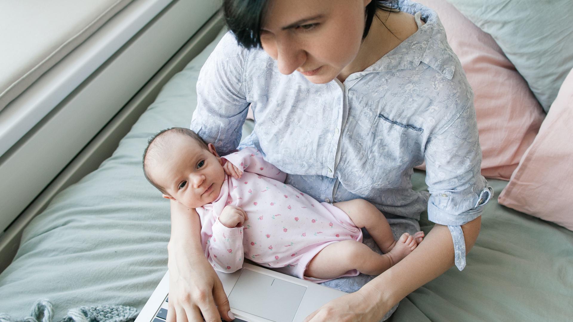 Mutter mit Neugeborenem am Laptop