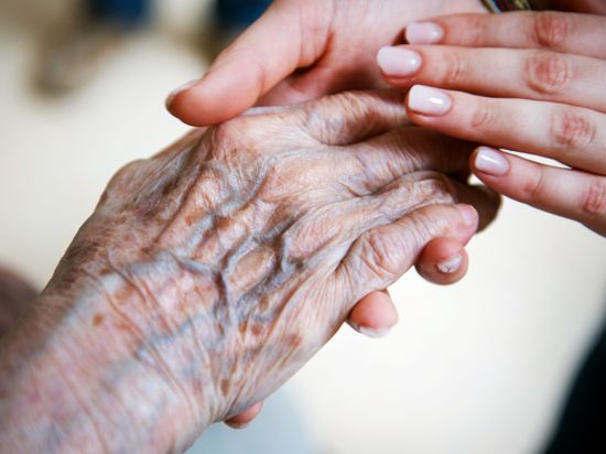 Eine Frau hält die Hand eines Senioren.