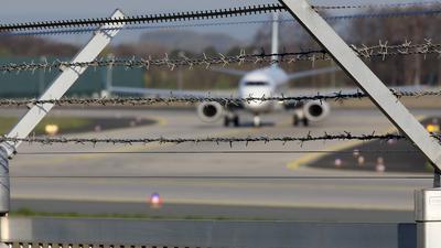 Ein Flugzeug auf dem Flughafen Frankfurt a.M., im Vordergrund ein Sicherheitszaun mit Stacheldraht.