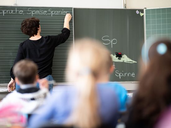 Eine Lehrerin schreibt in einer Schule an die Tafel.