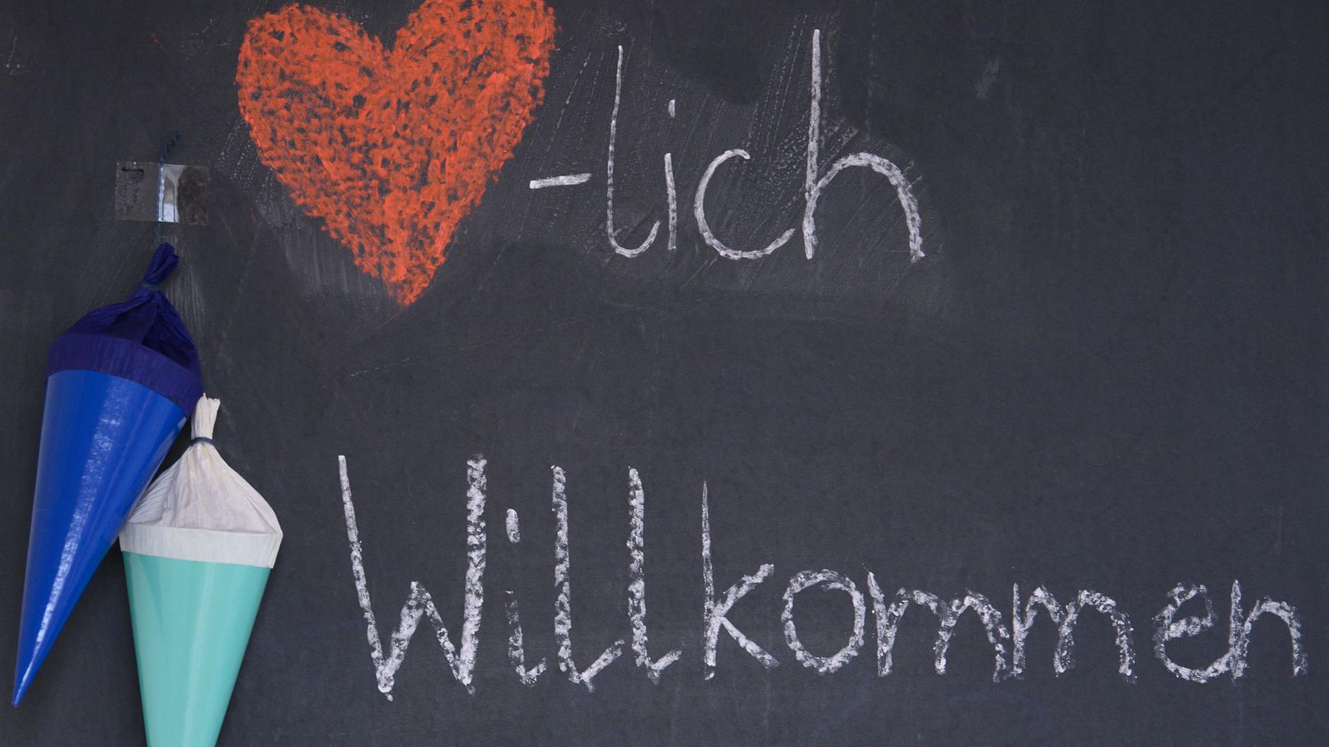 "Herzlich Willkommen“ steht zu Beginn des neuen Schuljahrs mit Kreide auf der Tafel eines Klassenzimmers.