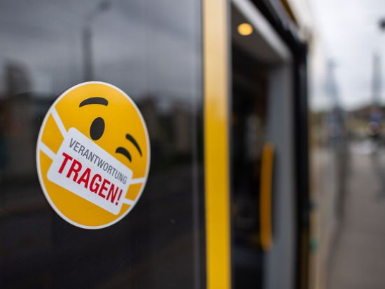 Ein Smiley-Aufkleber mit einem Mundschutz und der Aufschrift „Verantwortung tragen“ klebt an einer Scheibe einer Straßenbahn.