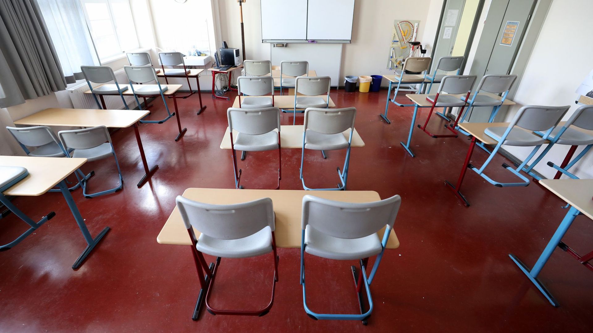 Die Stühle in einem leeren Klassenzimmer stehen auf den Tischen.