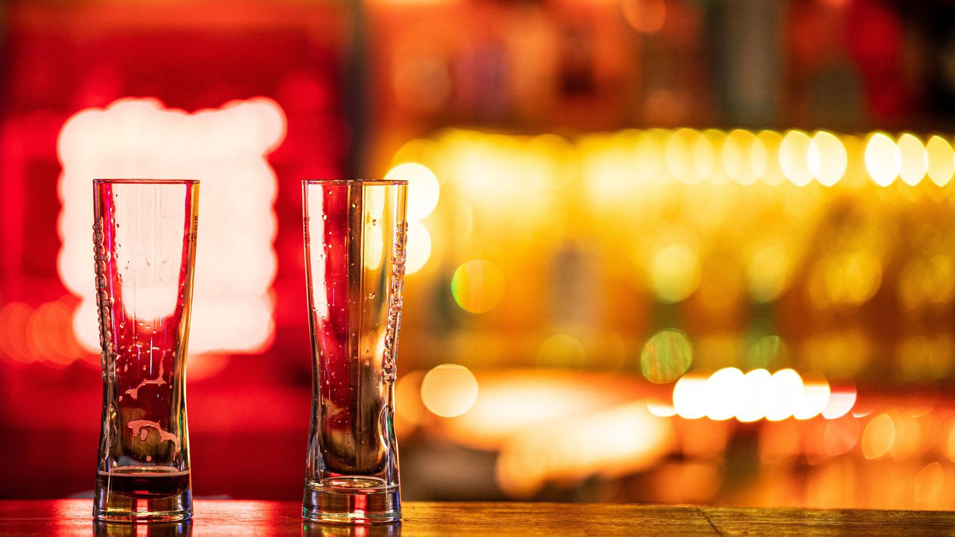 Zwei leere Gläser stehen auf einem Tresen in einer Bar.