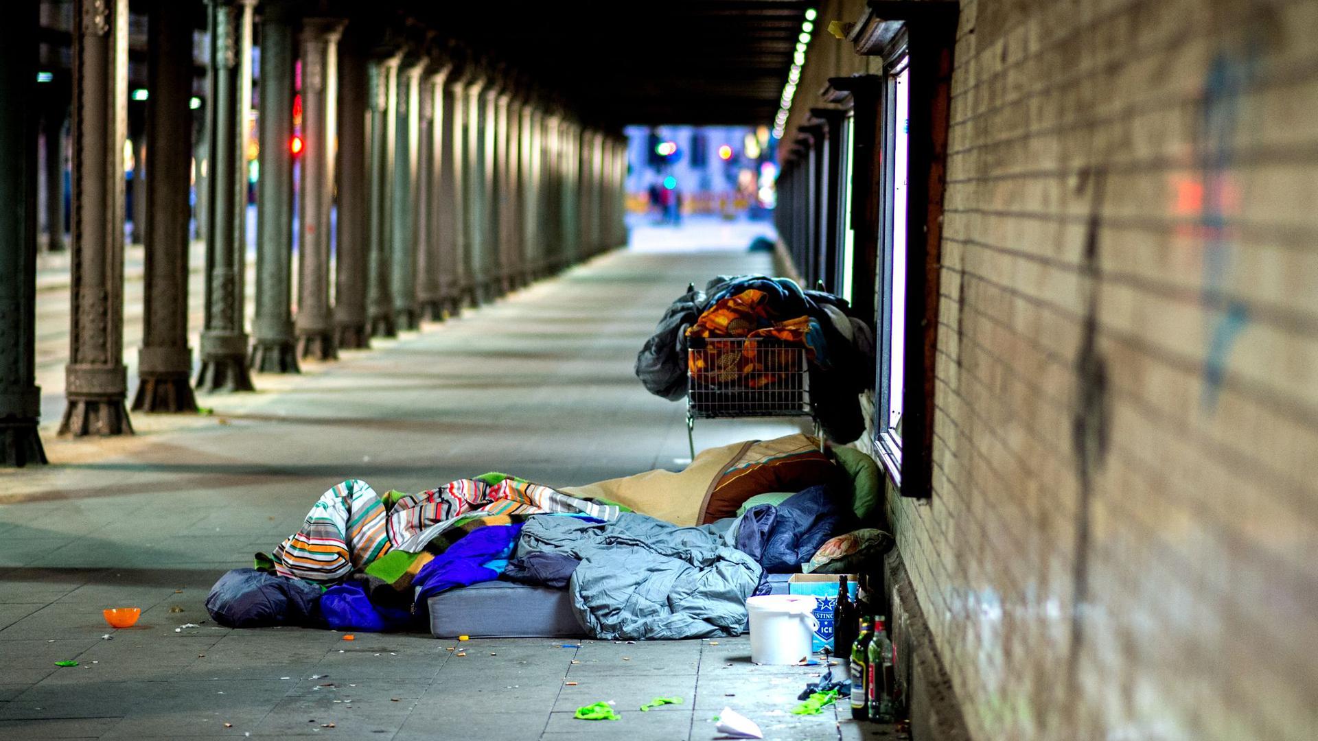 Obdachlose liegen unter einer Eisenbahnunterführung.