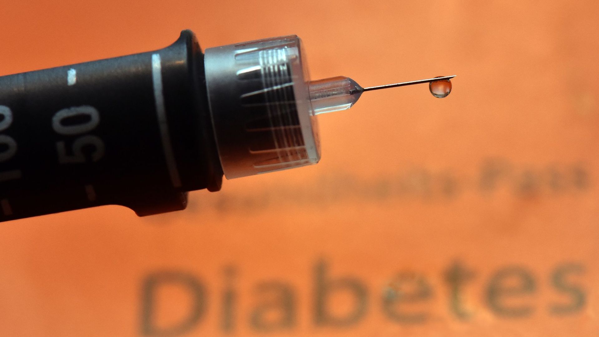 Ein Tropfen Insulin hängt an der Nadel einer Spritze für Diabetiker.