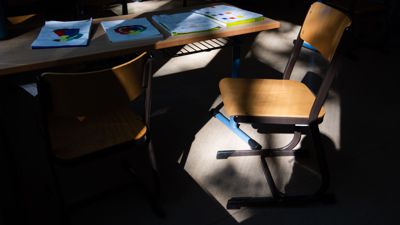 Ein Stuhl steht in einem leeren Klassenraum auf einem Tisch.