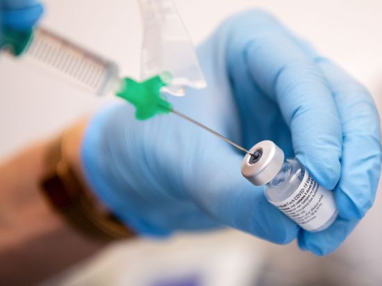 Eine Klinik-Mitarbeiterin zieht den Covid-19 Impfstoff von Biontech/Pfizer für eine Impfung auf eine Spritze.
