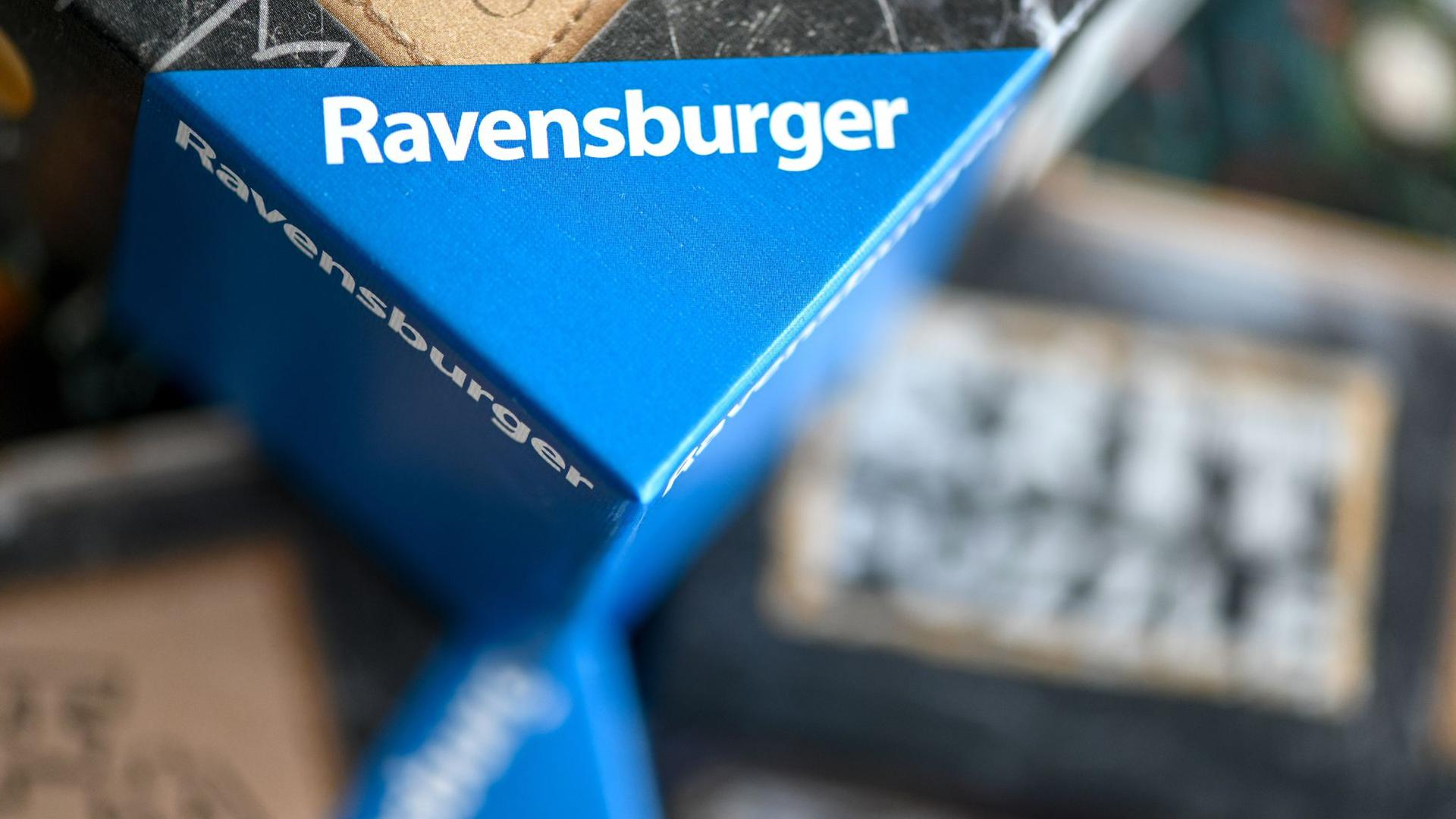 Spiele der Marke Ravensburger liegen übereinander auf einem Tisch.