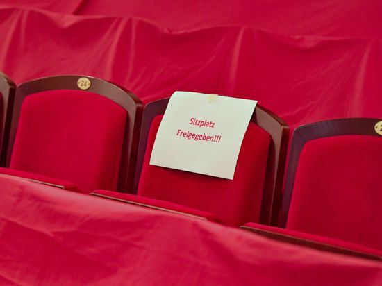 Ein Zettel mit der Aufschrift „Sitzplatz Freigegeben!!!“ hängt an einem Sitzplatz im leeren Zuschauerraum eines Theaters.