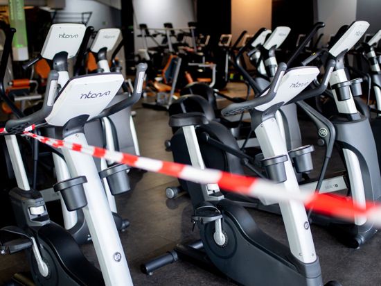 Ein rot-weißes Flatterband ist an Fahrradtrainern befestigt, die in einem Fitnessstudio stehen.