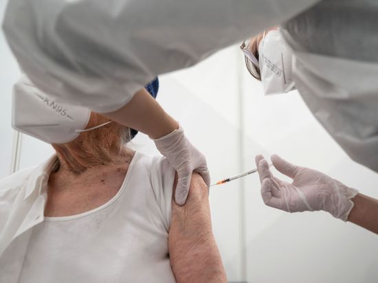 Eine Krankenpflegerin impft im Impfzentrum in der Paul-Horn-Arena in Tübingen eine Frau.