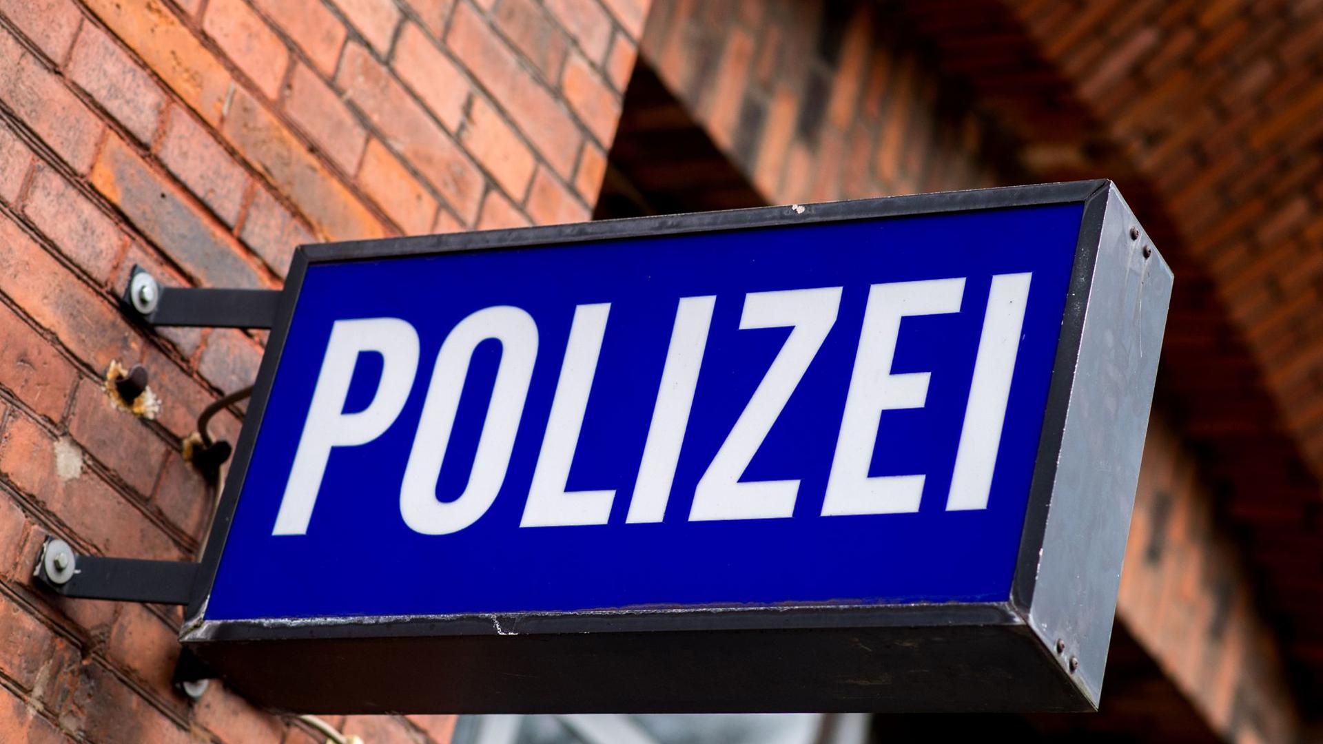 Der Schriftzug „Polizei“ auf einem Schild am Gebäude einer Polizeiinspektion.