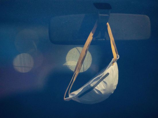 Eine Maske hängt am Rückspiegel eines Autos in Stuttgart.