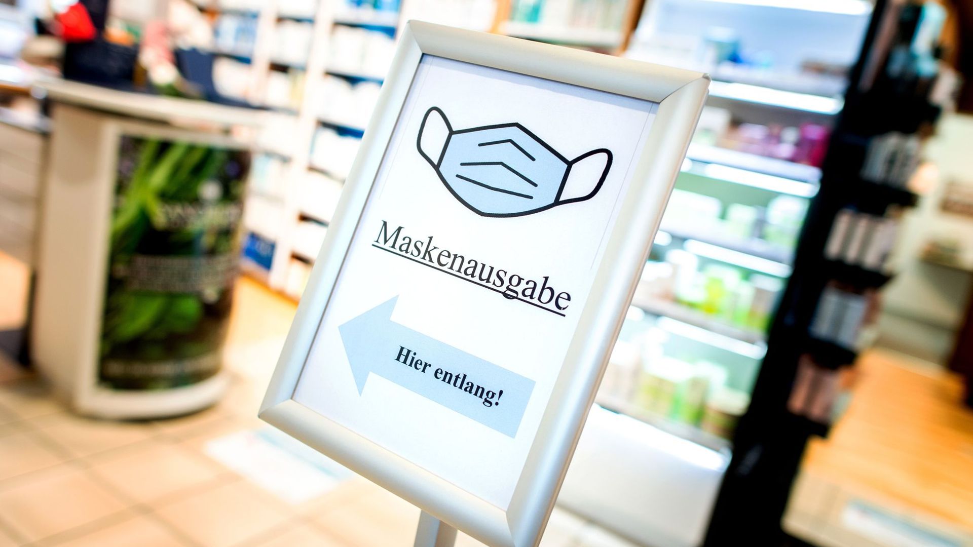 Ein Schild mit der Aufschrift „Maskenausgabe“ steht im Eingang einer Apotheke.