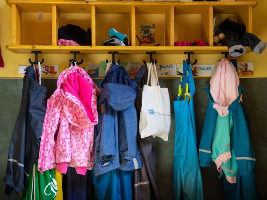 Jacken und Taschen hängen im Eingangsbereich in einem Kindergarten.