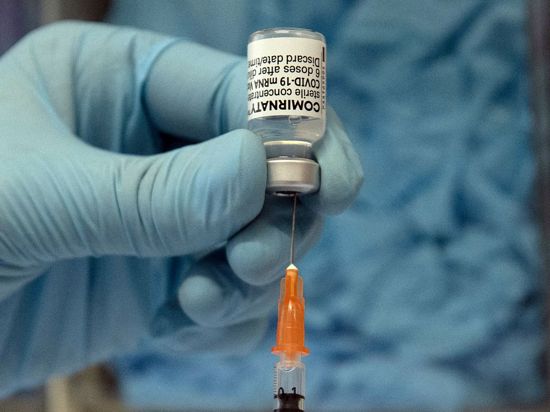 In einer Hausarztpraxis wird eine Spritze mit dem Biontech-Impfstoff Comirnaty aufgezogen.