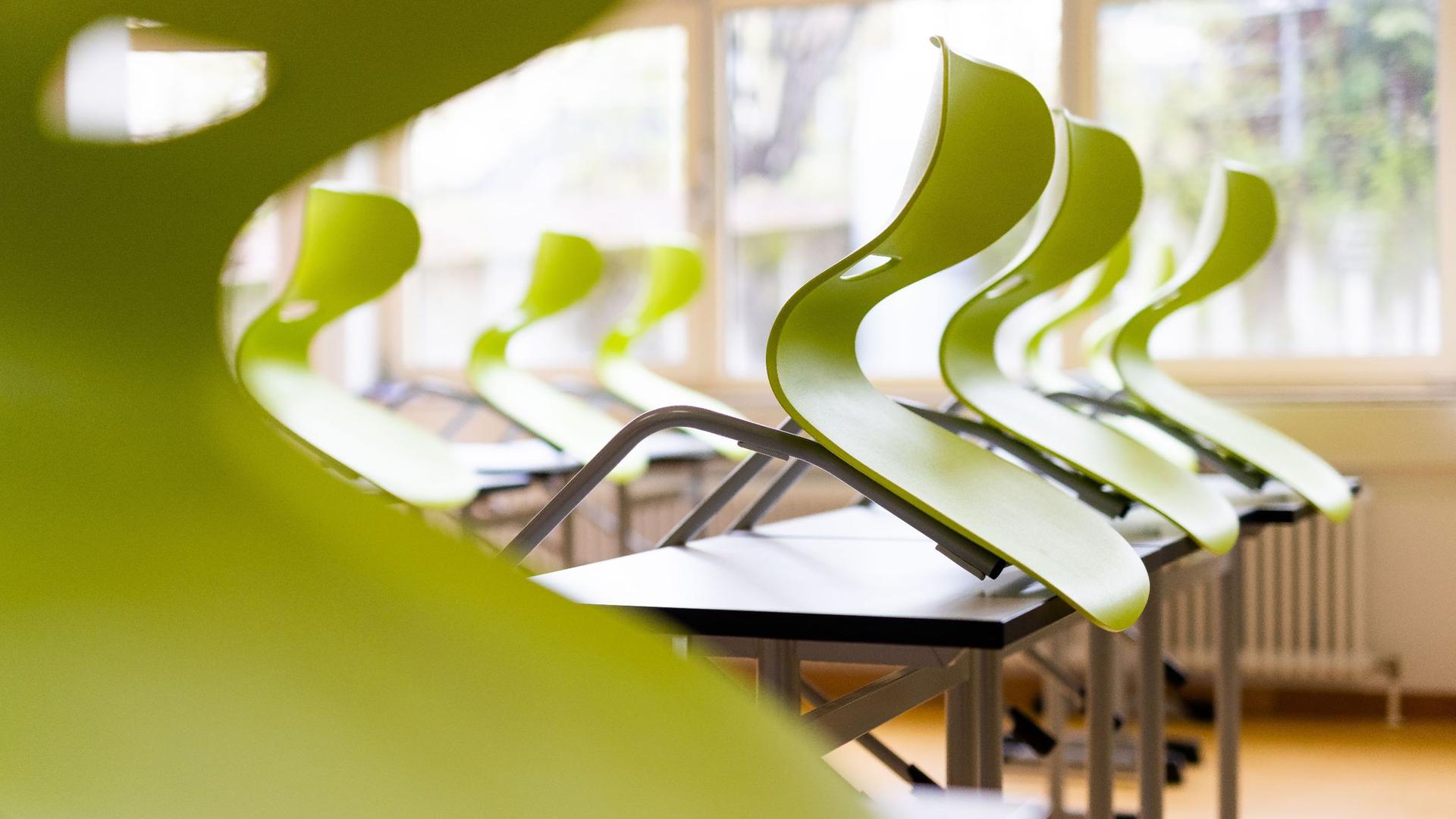 Stühle stehen auf Tischen in einem leeren Klassenzimmer.