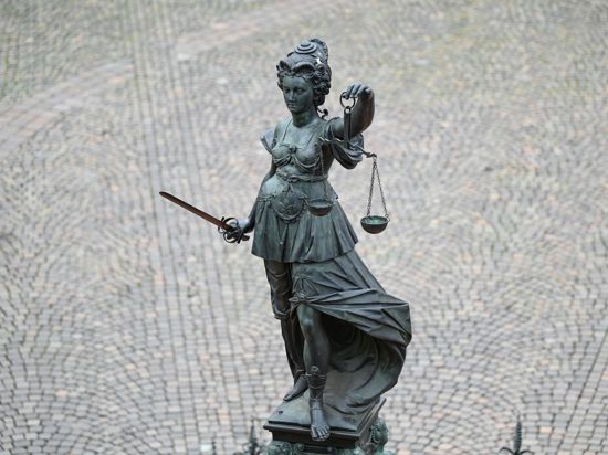 Die Statue der Justitia steht mit einer Waage und einem Schwert auf einem Platz.