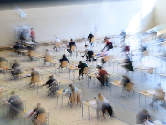 Mit weitem Abstand sitzen Schüler zur Abiturprüfung an ihren Tischen.