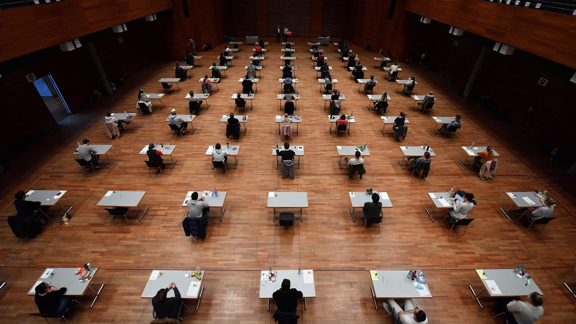 Studierende sitzen während einer Prüfung in einer Halle.