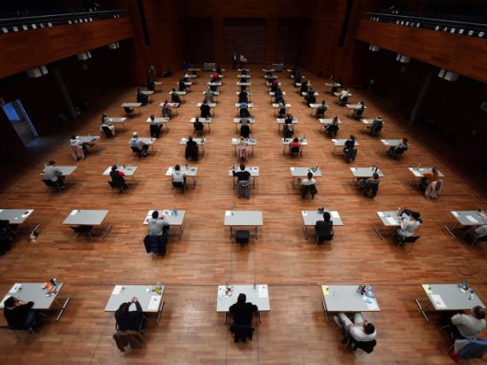 Studierende sitzen während einer Prüfung in einer Halle.