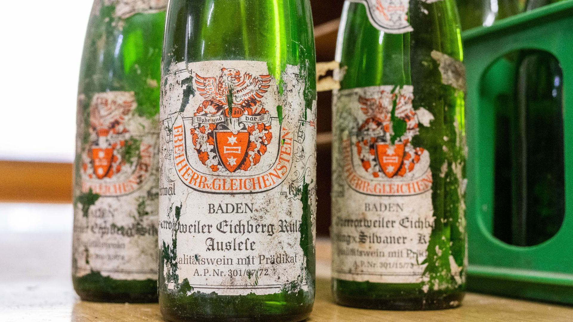Alte Weinflaschen mit verwitterten Etiketten stehen im Weingut Freiherr von Gleichenstein auf einem Tisch.