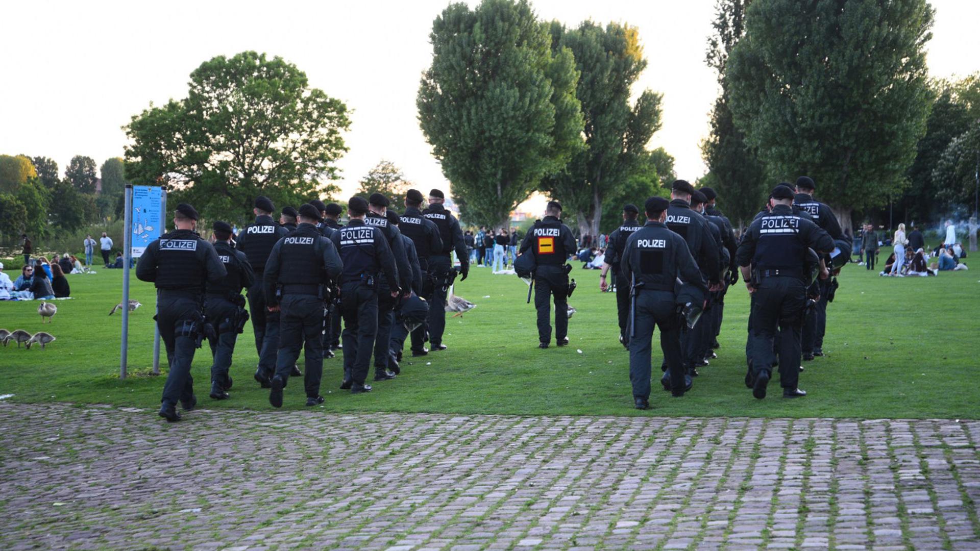 Polizeibeamte gehen über die Neckarwiese.