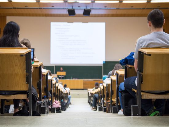 Studentinnen und Studenten sitzen während einer Vorlesung in einem Hörsaal.