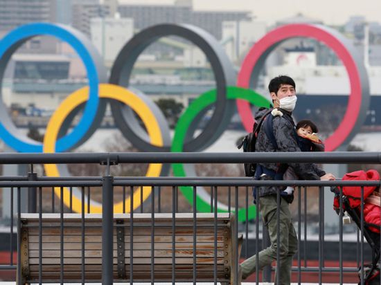 Ein Mann läuft an den Olypischen Ringen vorbei.