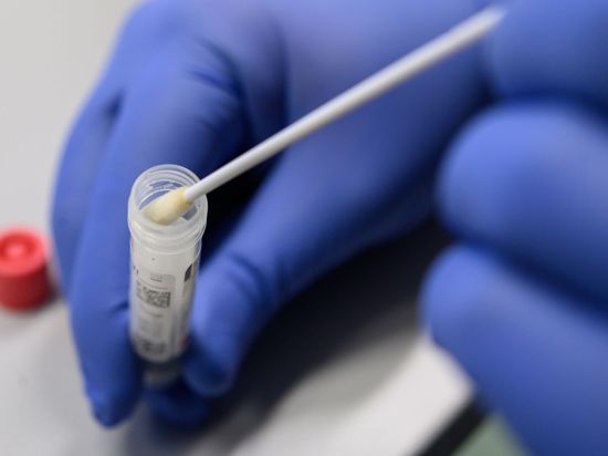 Ein medizinischer Mitarbeiter legt einen Tupfer mit einem Abstrich für einen Corona-Test in ein Röhrchen.