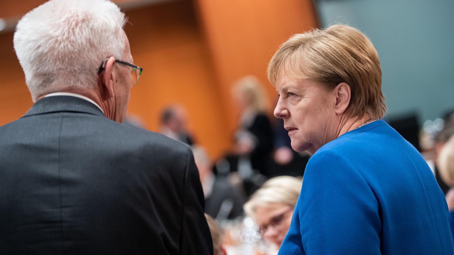 Winfried Kretschmann steht neben Angela Merkel