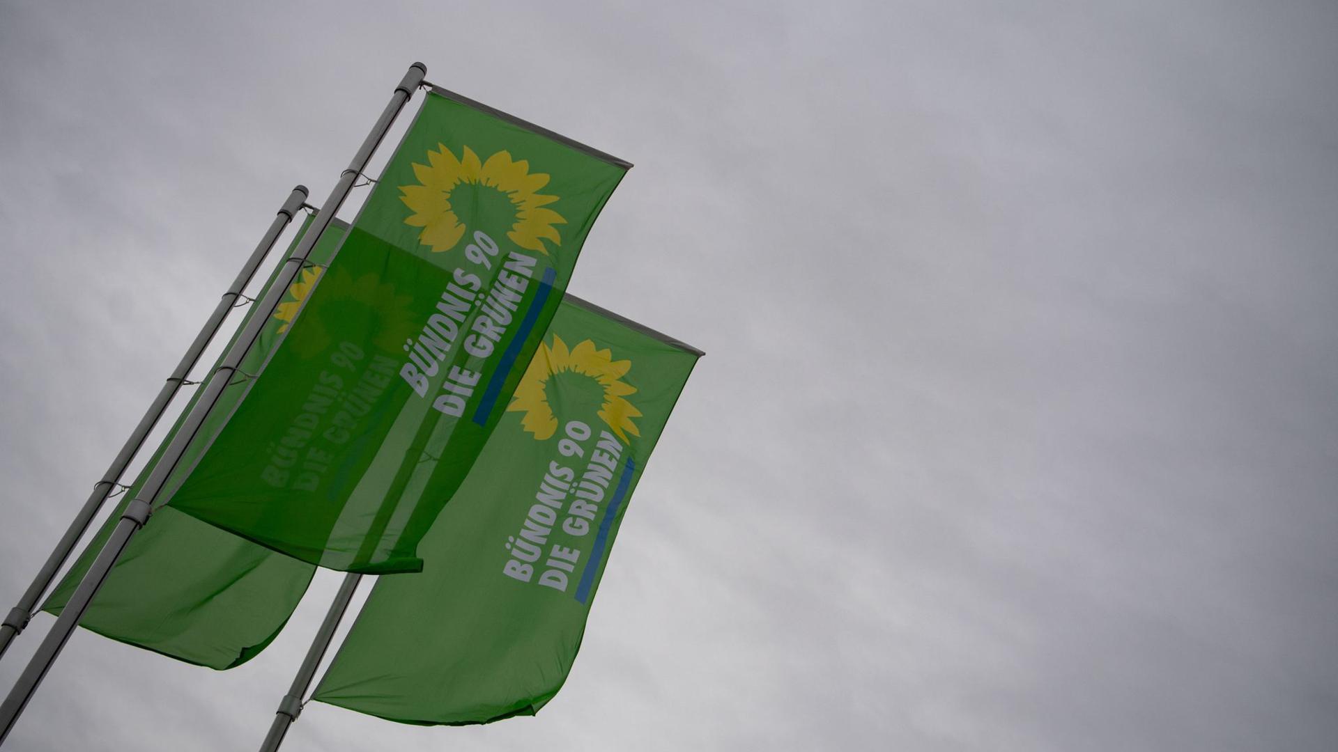 Flaggen mit dem Logo von Bündnis 90/Die Grünen wehen vor einem Veranstaltungszentrum.