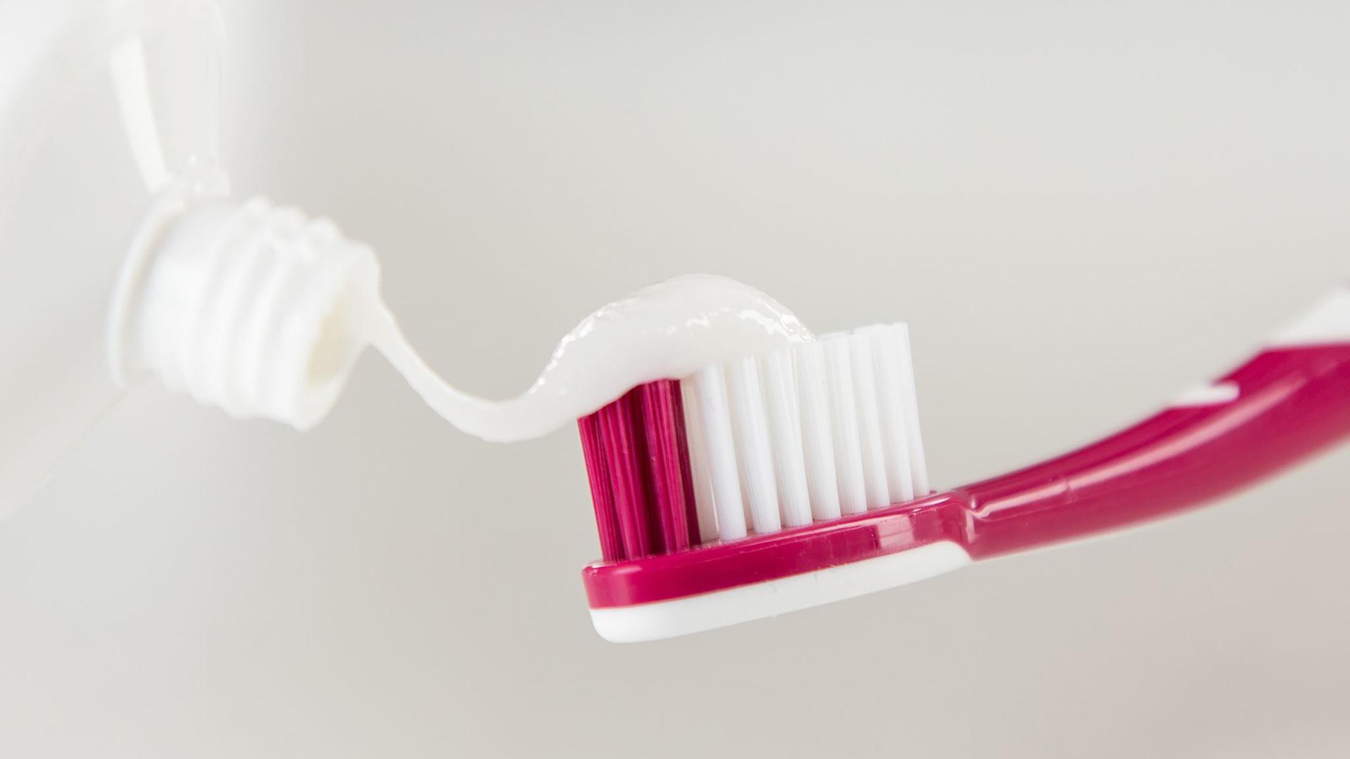 Zahnpasta wird auf eine Zahnbürste aufgetragen.