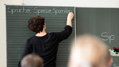 Eine Lehrerin in Baden-Württemberg schreibt in einer Schule an eine Tafel.