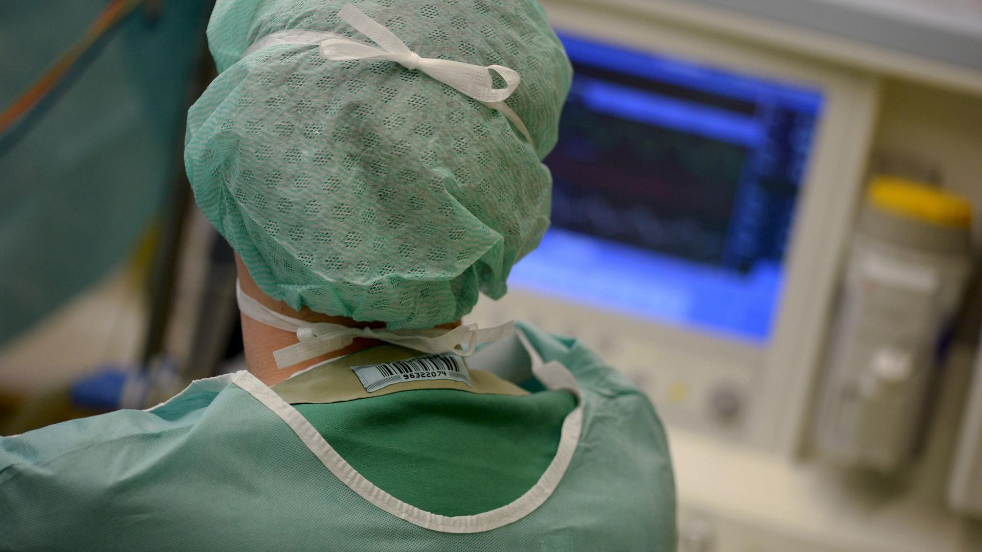 Ein Mediziner schaut während einer Operation auf einen Überwachungs-Monitor.