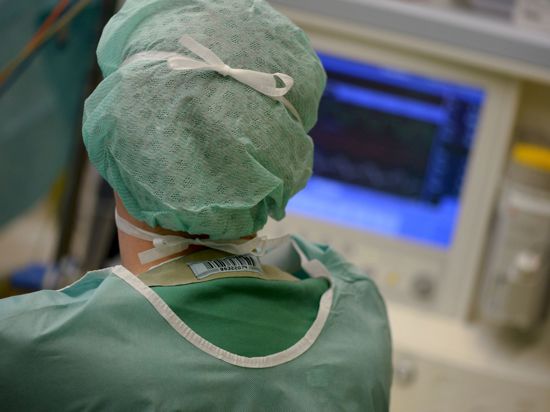 Ein Mediziner schaut während einer Operation auf einen Überwachungs-Monitor.
